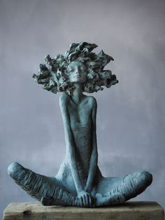 a woman sitting on top of a wooden block with flowers in her hair over her head