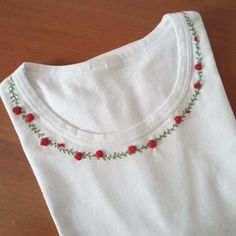 a white t - shirt with red roses on the front and green leaves on the back