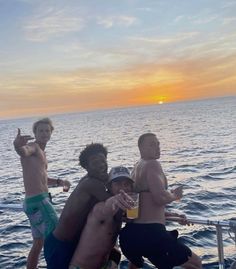 four men standing on the back of a boat in the ocean with their arms around each other