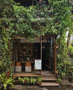 an outdoor bar with plants growing on the wall and steps leading up to it's entrance