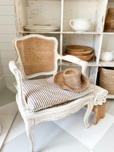 an old chair with a hat on top of it in front of a bookcase