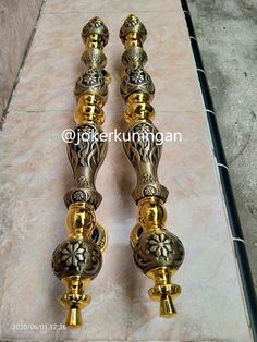 two golden candlesticks sitting on top of a marble floor next to each other