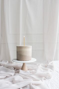 a white cake sitting on top of a table with a candle in the middle of it