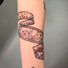 a woman's arm with a flowered film strip tattoo on it