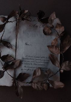 an old piece of paper with leaves on it and a note attached to the side