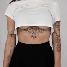 a woman with tattoos on her stomach wearing a white crop top