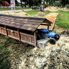 a toy truck is parked in front of a wooden structure with a roof on it