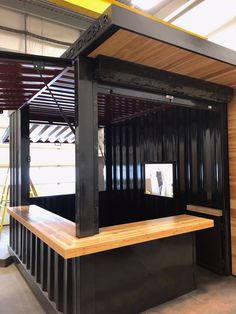 the inside of a shipping container with wooden flooring and black metal structure on top