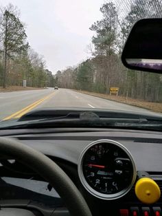 the dashboard of a car on a road with trees in the background