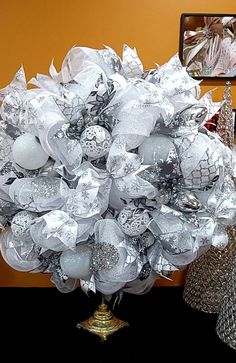 a bouquet of silver and white flowers on a table in front of a wall with pictures