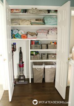 the closet is full of clothes and other items for cleaning or storage, as well as several bins