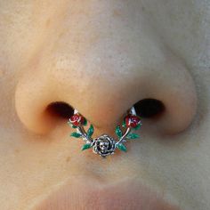 a close up of a person's nose with a rose on it and two piercings