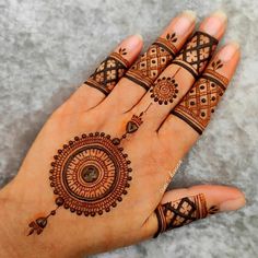 a woman's hand with henna tattoos and rings on her fingers, showing the intricate design