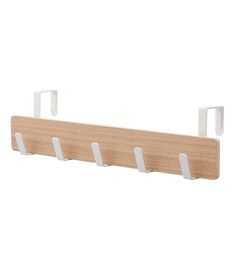 a wooden shelf with three white hooks on it