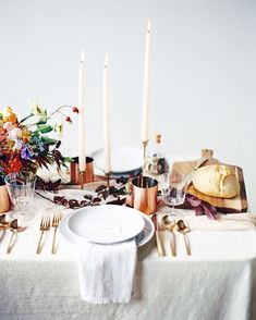 the table is set with candles, plates and silverware