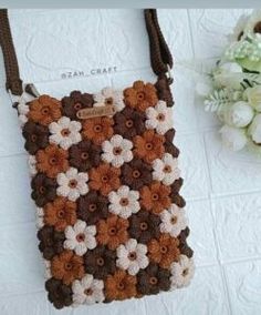 a crocheted purse sitting on top of a white table next to a bouquet of flowers