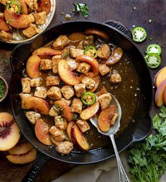 a skillet filled with meat and peaches on top of a table