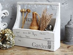 an old wooden crate with gardening items in it on a table next to a potted plant