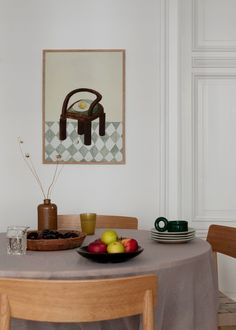 the table is set for two with plates and fruit on it in front of a painting