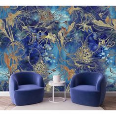 two blue chairs sitting next to each other in front of a wall with flowers on it