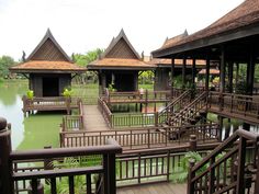 a wooden walkway leads to several pavilions on the water