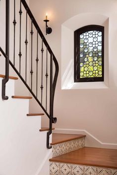 the stairs are made of wood and have wrought iron handrails with stained glass window