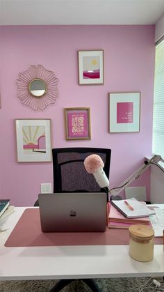 a laptop computer sitting on top of a white desk in front of a pink wall