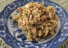 a blue and white plate topped with pasta covered in almonds on top of a table