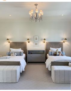 two beds in a room with lamps on the ceiling and pillows on the bedding