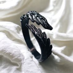 two black bracelets sitting on top of a white sheet