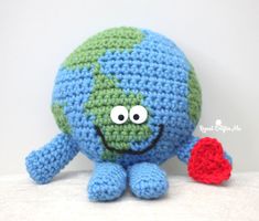 a crocheted blue and green stuffed animal with a red heart