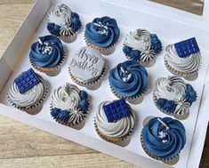 twelve cupcakes with blue and white frosting in a box