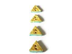 three pieces of cheese are arranged in the shape of pyramids on a white surface