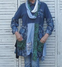 a woman standing in front of a white wall with her hands on her hips wearing jeans and a scarf