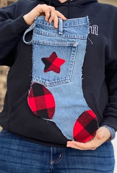 a person holding up a pair of jeans with red and black plaid stars on them