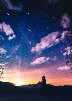 a person sitting on top of a hill under a sky filled with stars