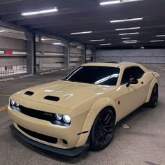 a tan sports car parked in a parking garage next to an empty parking space with lights on