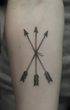 an arrow tattoo on the arm with three arrows pointing in different directions, and one is black