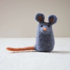 a small gray mouse sitting on top of a bed