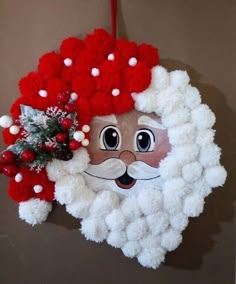 a santa clause wreath hanging on the wall with red and white pom - poms