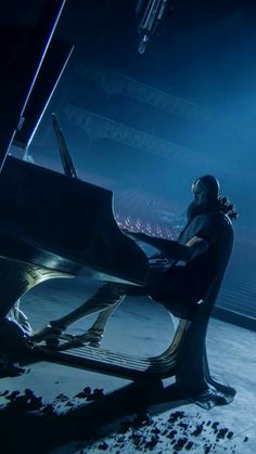 a man sitting at a piano in front of a stage with lights and snow on the ground