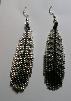 two pairs of beaded earrings are displayed on a white surface, one is black and the other is silver