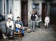 an old photo of two adults and three children in front of a building with doors