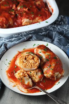 two white plates filled with stuffed shells covered in sauce