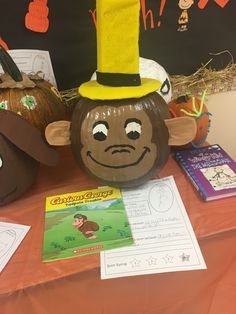 a table with pumpkins, paper mache and an animal mask on it's head