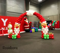 balloon arch with santa clause and snowman on it in an indoor event space for children to play