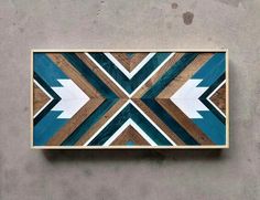 a wooden wall hanging on the side of a building with an arrow design painted on it