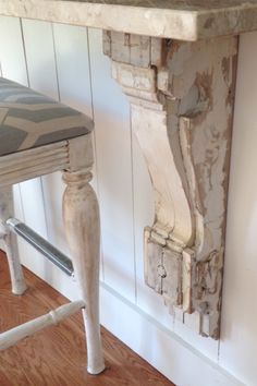 an old wooden table and stool in a room with white walls, wood floors and hardwood flooring