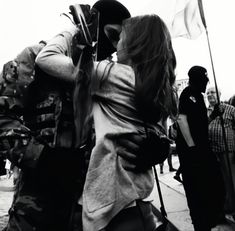 a man and woman kissing in front of a group of people on the street with flags