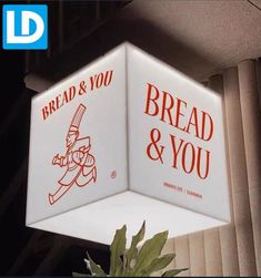 bread and you sign hanging from the side of a building in front of a plant